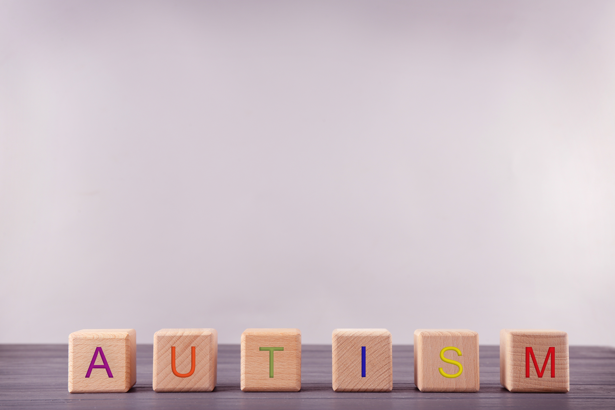 https://fdna.health/knowledge-base/what-are-the-main-symptoms-of-autism-in-girls/wooden-cubes-with-word-autism-on-light-background/